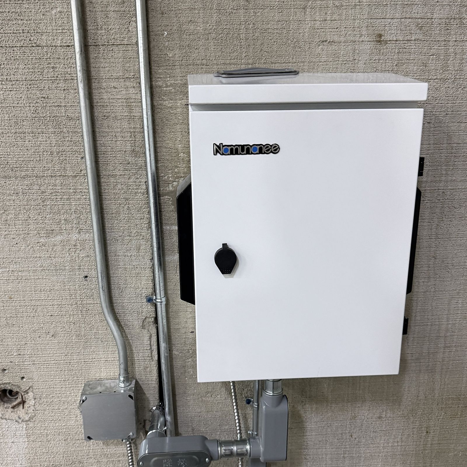 Wall-mounted equipment enclosure with neat metal conduit on concrete