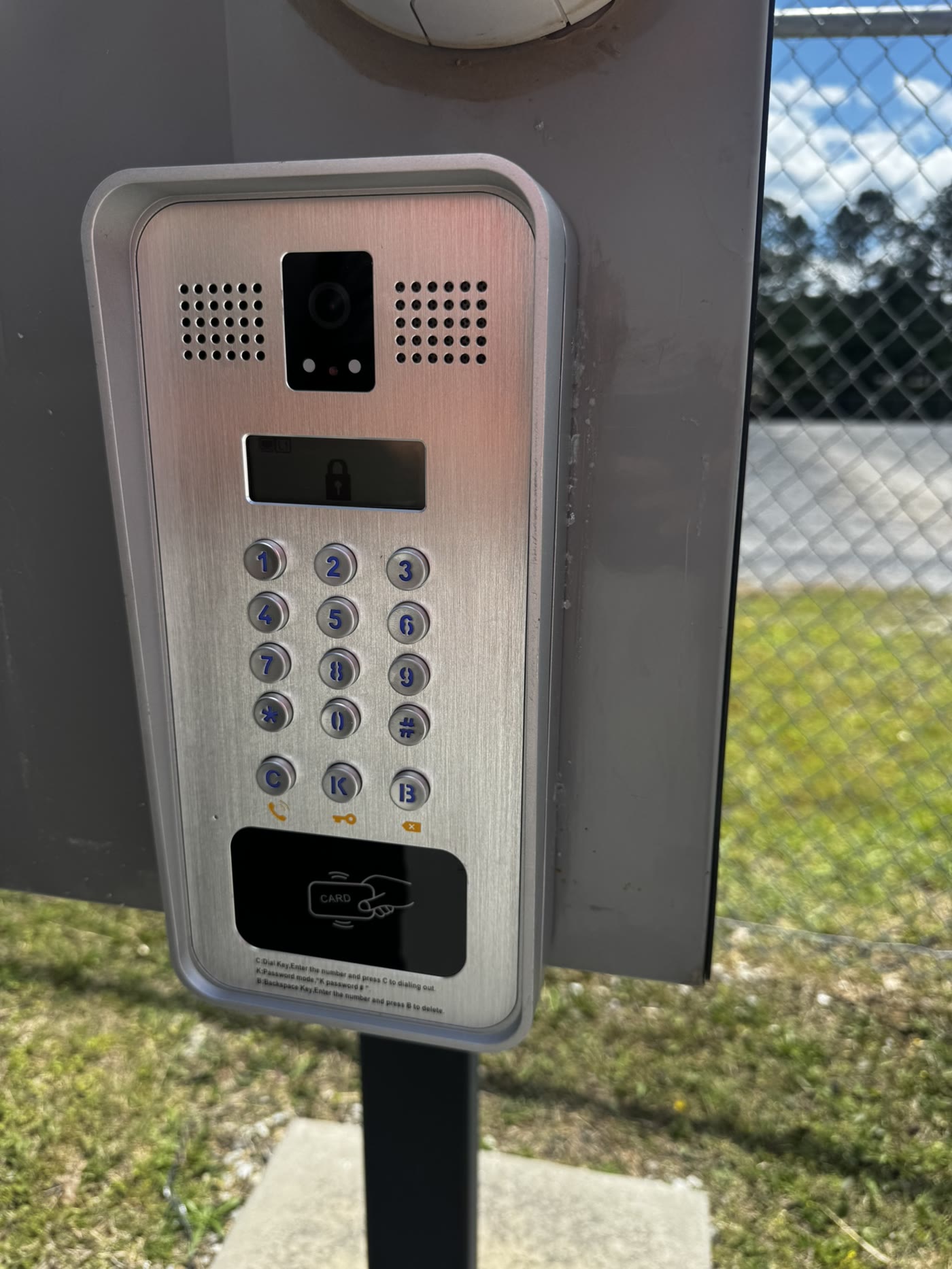 Stainless video intercom keypad with card reader on a gooseneck post at a gated entry